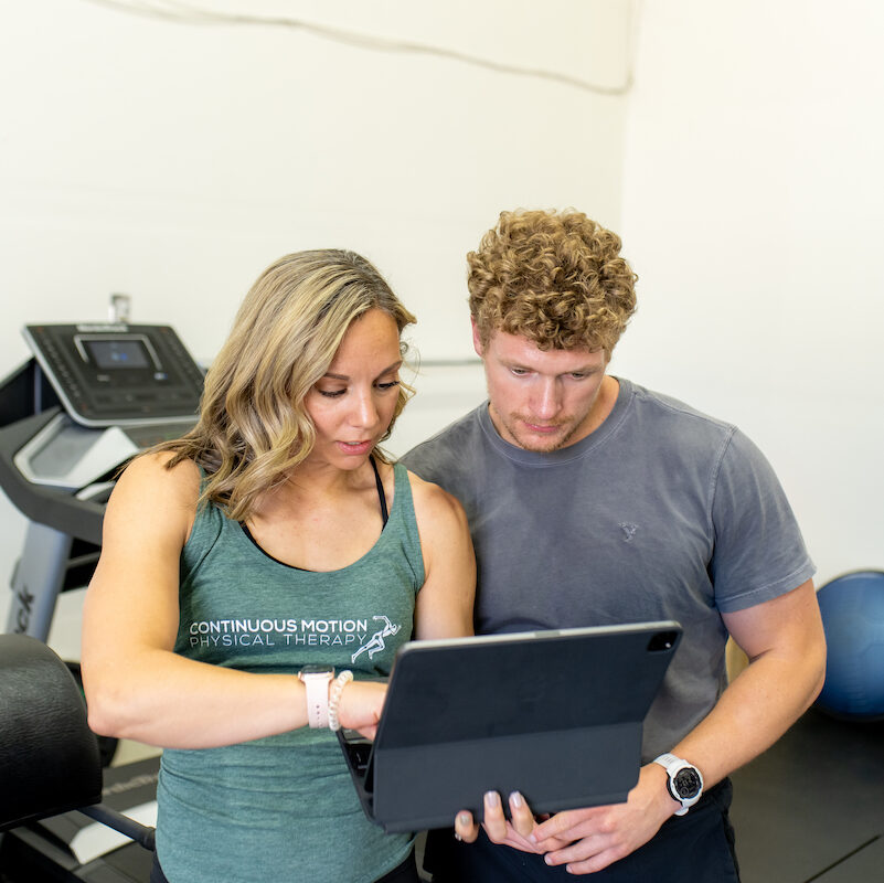 A man and woman looking at an ipad in a gym.