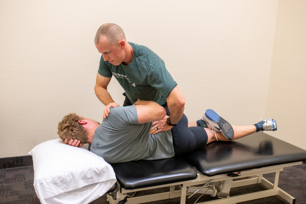 A man is having his back examined by a physical therapist.