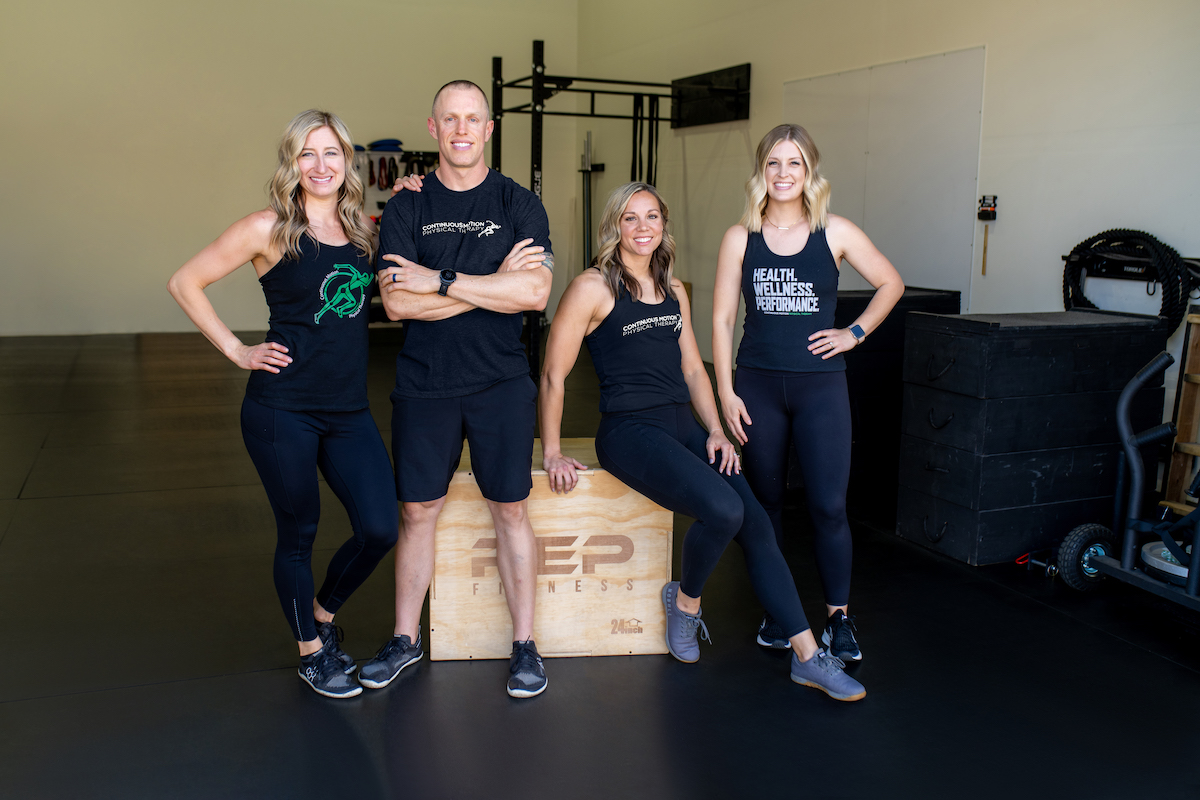 Four people posing in front of a box in a gym.