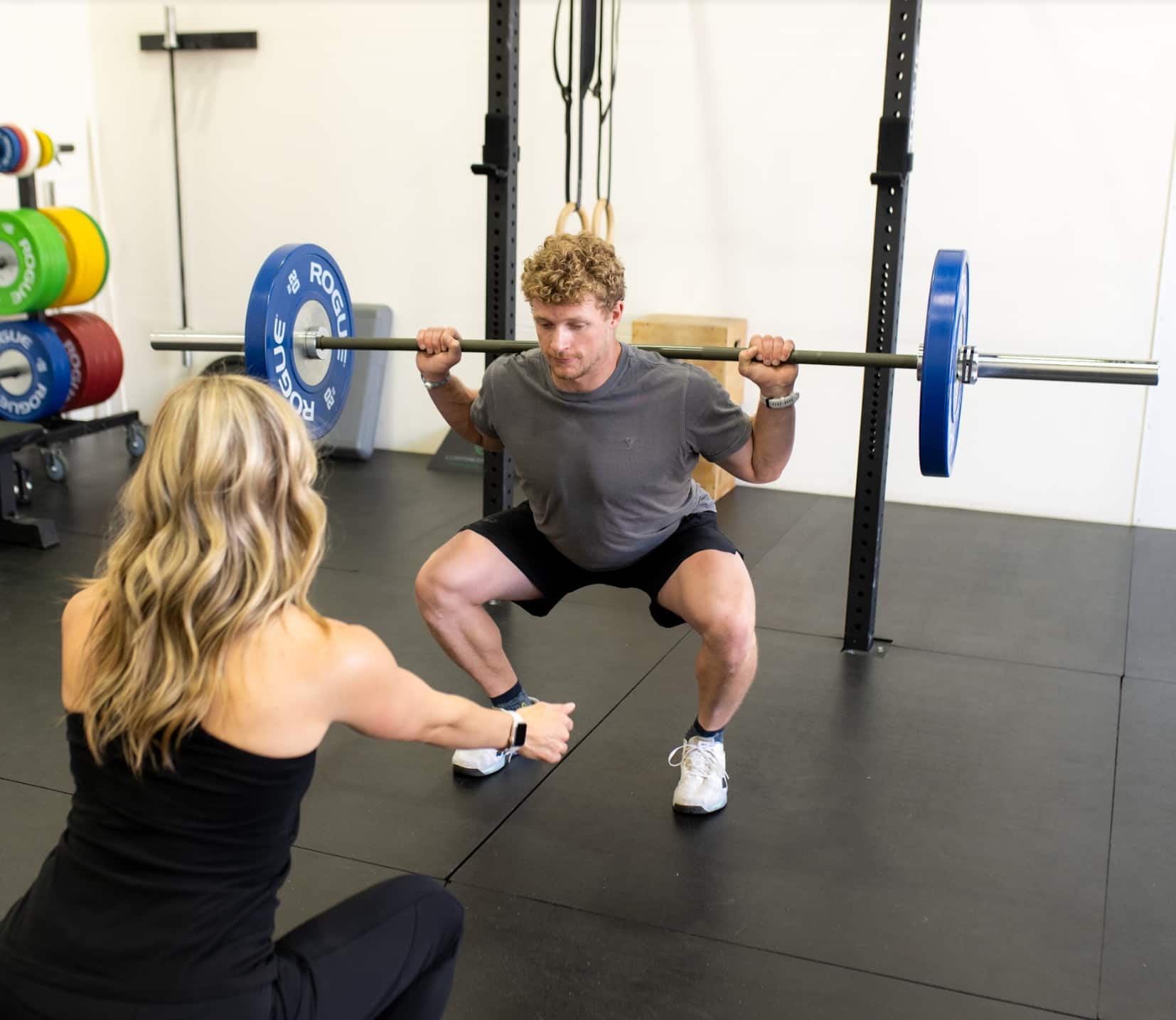 A woman squatting with a barbell in a gym.